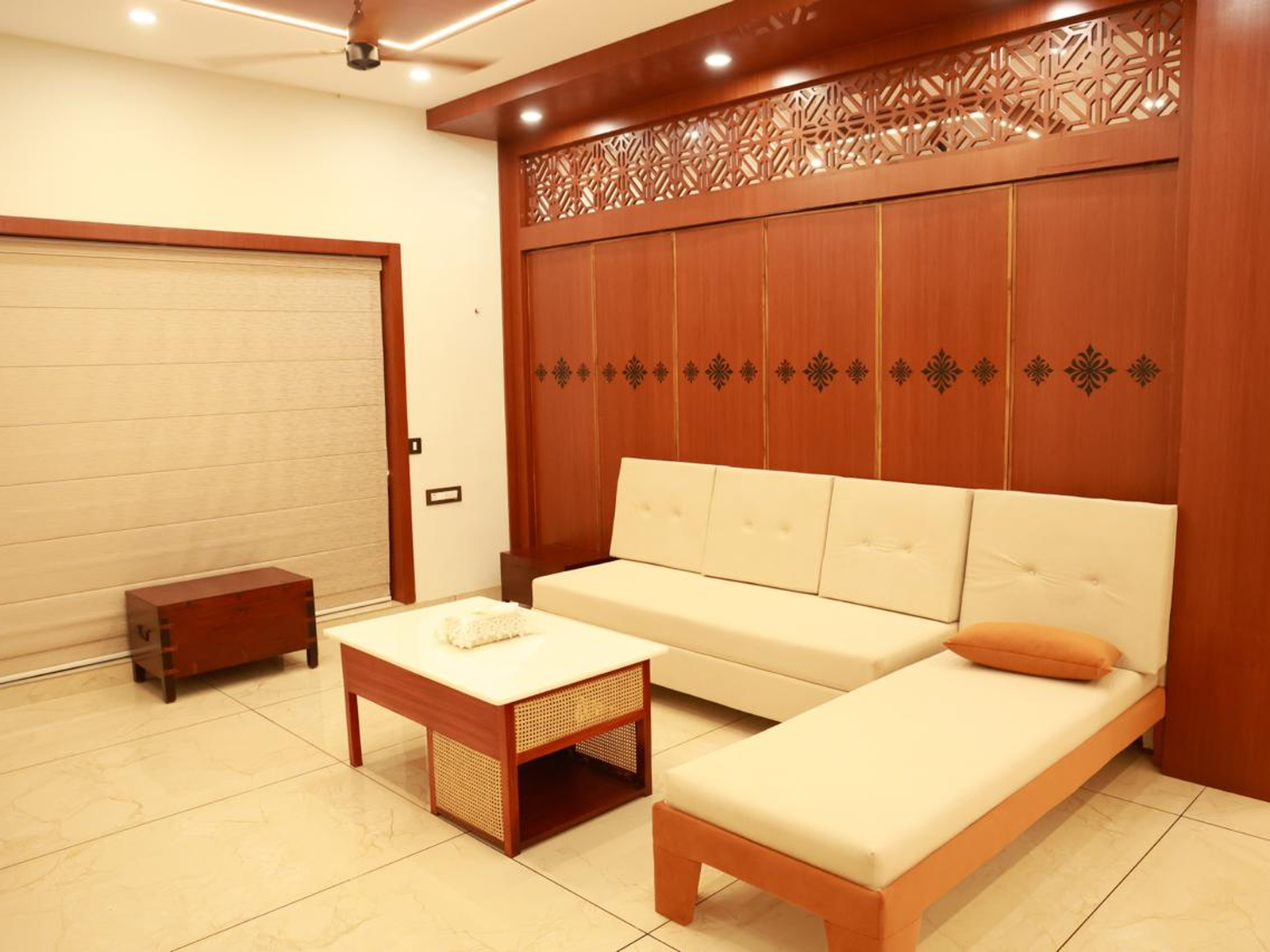 Cream-colored modern sofa set against a large wood-paneled wall with traditional carved lattice details.