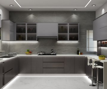 Sleek charcoal grey kitchen with white countertops, grey stone backsplash, integrated LED floor lighting, and a breakfast nook with bar stools.